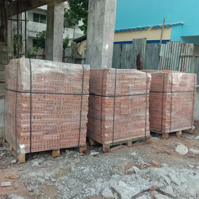 The red construction bricks are packed on pallets and stacked in sets of three at the construction site, making them easy to move and store.