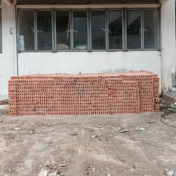 Large stacks of red clay bricks are piled up in front of the warehouse, with a full stock ready for immediate delivery, ideal for project work and contractors requiring large quantities.